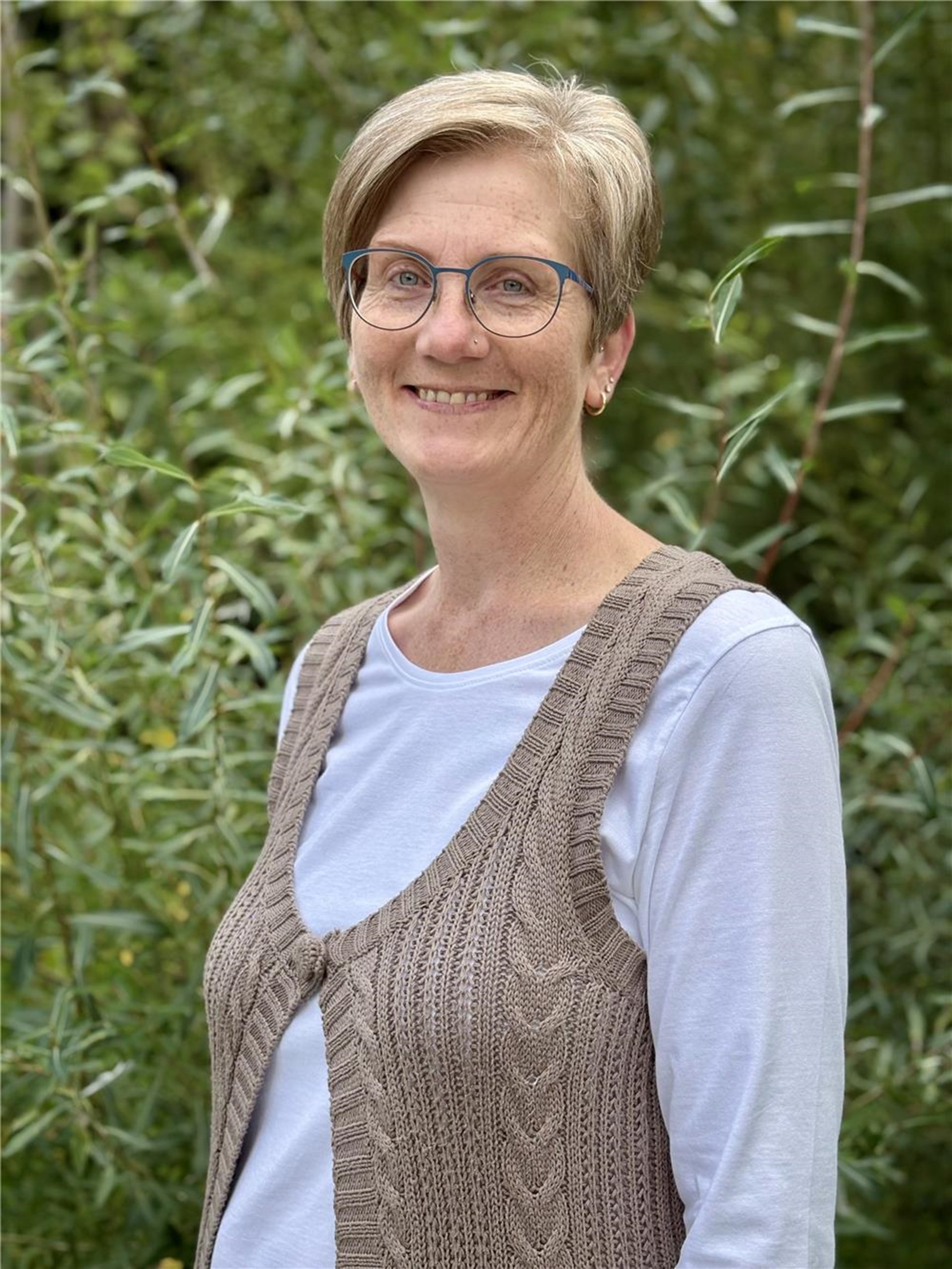 Eine Frau mit kurzen Haaren und Brille ist zu sehen.