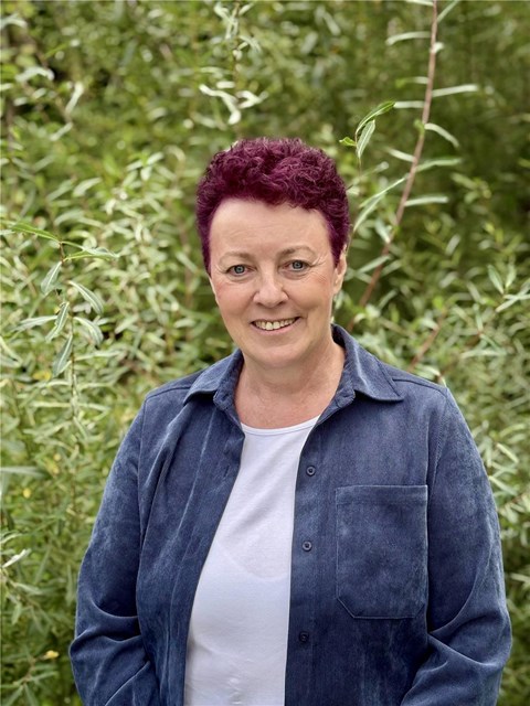 Es ist eine Frau mit lila Haar zu sehen.